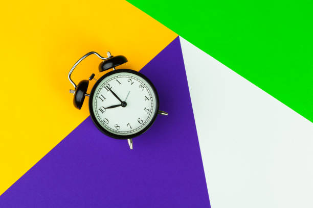 istock Black alarm clock on color block background, office interior 1329655120