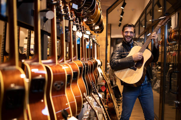 istock Talented caucasian musician in leather jacket checking and testing new guitar instrument he wants to buy in music shop. 1329656668