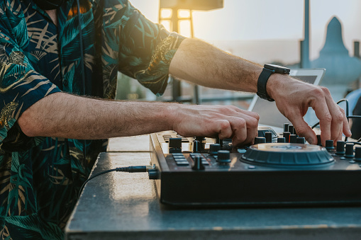 Close-up of the hands of a DJ playing music on a terrace