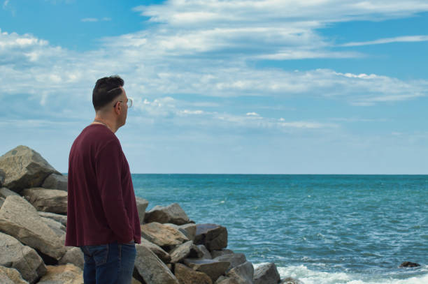 istock man on the seashore looking the horizon 1329658542