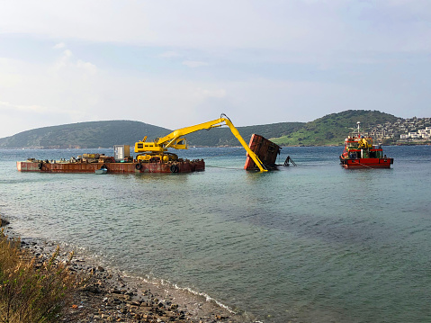 floating crane working on wreck near coastline