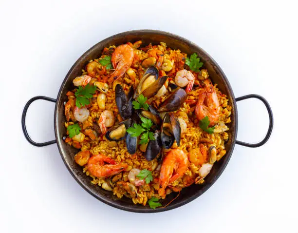 Traditional spanish seafood paella with rice, mussels, shrimps in a pan on white background. view from above, flat lay