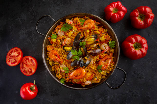 istock Traditional spanish seafood paella with tomatoes on a black background 1329666836