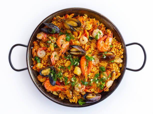 Traditional spanish seafood paella in the fry pan on a white background Traditional spanish seafood paella with rice, mussels, shrimps in a pan on white background. view from above, flat lay cooking pan overhead stock pictures, royalty-free photos & images