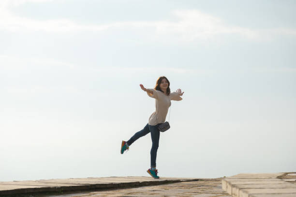 istock Young woman spreading hands wide open and walking on a mountain path 1329667948