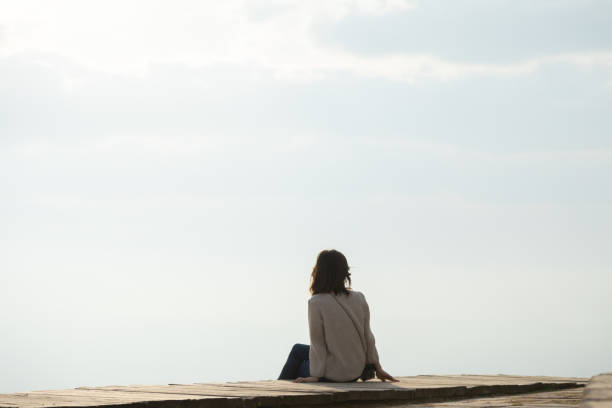istock Young woman sitting on edge mountain 1329668017