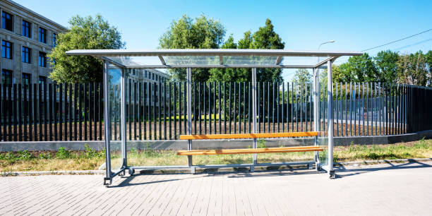 istock Empty urban bus stop with wooden bench stands on tiled sidewalk 1329669563