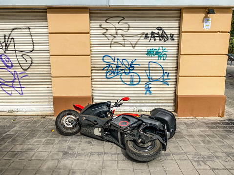 Valencia, Spain - July 11, 2021: Electric scooter for rent fallen on the sidewalk. When people leave it they don't secure them properly and the wind cause them to fall