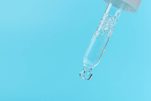 istock face serum drop with bottle on blue background. 1329673708