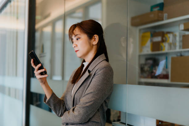 istock Young asian businesswoman using smartphone in office corridor 1329673812