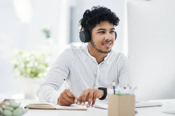 istock Shot of a young businessman writing notes while working on a computer in an office 1329679302