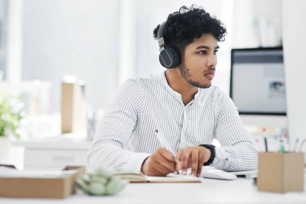 istock Shot of a young businessman writing notes while working on a computer in an office 1329679306
