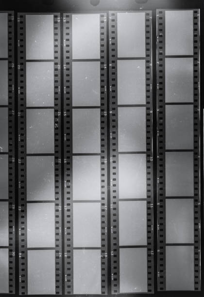 long 35mm black and white film strips on dark background behind protection foil with empty frames. cool photo placeholder, real macro photo of 35mm contact sheet. contact sheet stock pictures, royalty-free photos & images