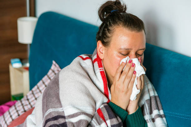 istock Unwell woman sneezing into tissue in home environment 1329681871