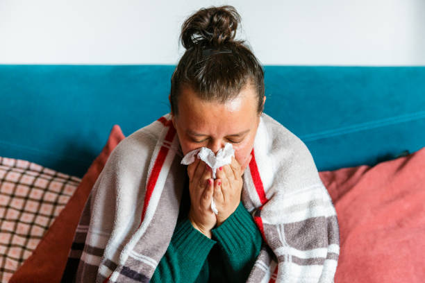istock Unwell woman sneezing into tissue in home environment 1329682546