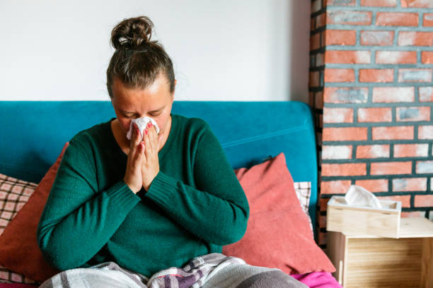 istock Unwell woman sneezing into tissue in home environment 1329682563