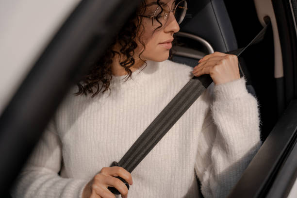 European girl buckles down seat belt in car European girl buckles down seat belt in car. Concentrated young curly woman wearing glasses. Concept of driving car seat belt photos stock pictures, royalty-free photos & images