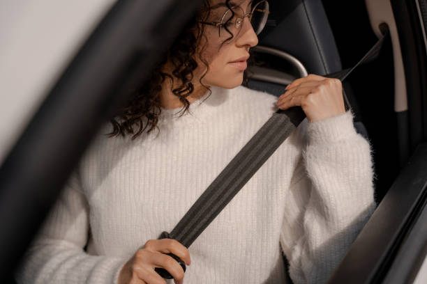 European girl buckles down seat belt in car European girl buckles down seat belt in car. Concentrated young curly woman wearing glasses. Concept of driving car seat belt stock pictures, royalty-free photos & images