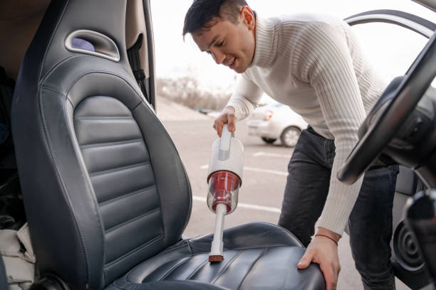 istock Man vacuuming car seat with vacuum cleaner in auto 1329682860