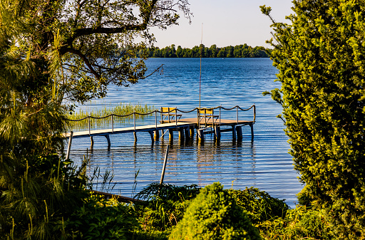 Panoramic summer view of Jezioro Selmet Wielki lake landscape with vintage pier reeds and wooded shoreline in Sedki village in Masuria region of Poland