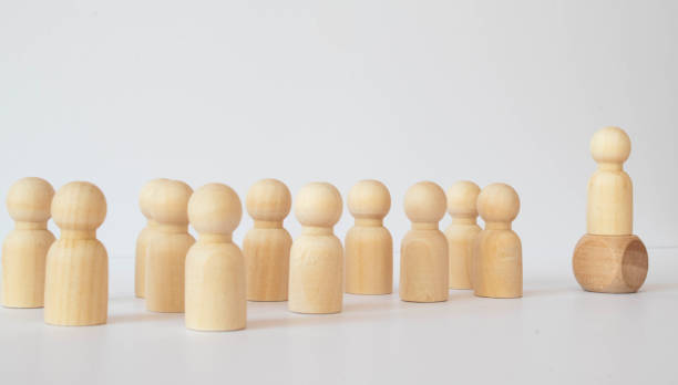 istock Small group of separated people seen from above represented anonymous with wooden figures on white background. 1329685573
