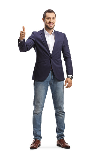 Full length portrait of a man in jeans and suit standing and showing thumbs up isolated on white background