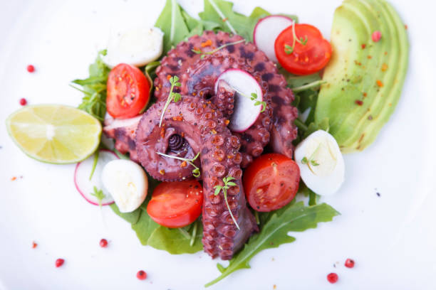 istock Warm salad with octopus, cherry tomatoes, avocado, arugula, quail eggs, radishes and lime on a white plate. Traditional Middle-Earth 1329687057