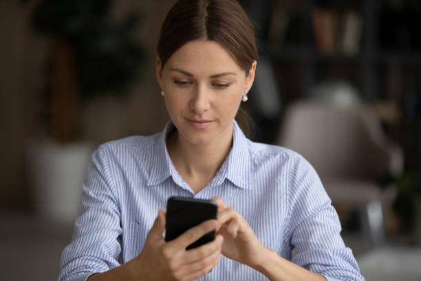 istock Beautiful young 30s woman using smartphone apps at workplace. 1329690266