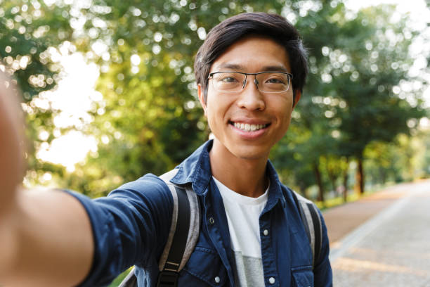 istock Happy asian male student in eyeglasses making selfie 1329690762