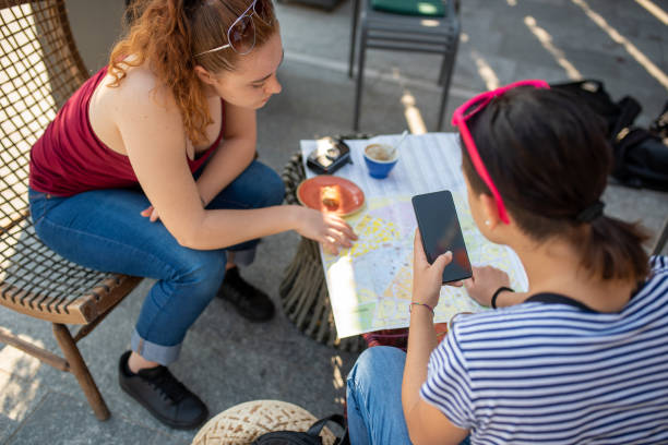 junge touristen, die die karte der stadt, die sie während ihrer reise besuchen, frühstückszeit an der bar mit fotos und smartphone-nutzung untersuchen - coffee couple italy drinking stock-fotos und bilder