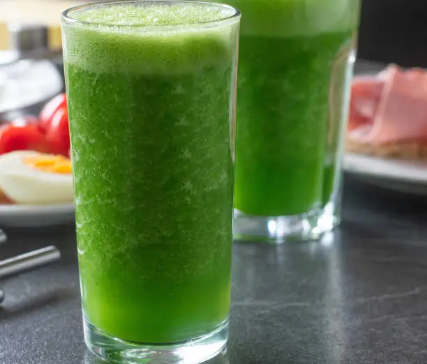 fresh blended green smoothie made with cucumber, green apple and lamb´s lettuce. Served in a glass. Closeup and front view