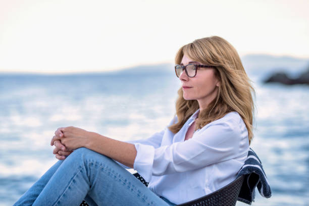 istock Woman daydreaming while relaxing by the sea 1329694298
