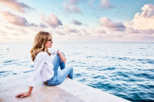 istock Attractive woman sitting by the sea 1329694302
