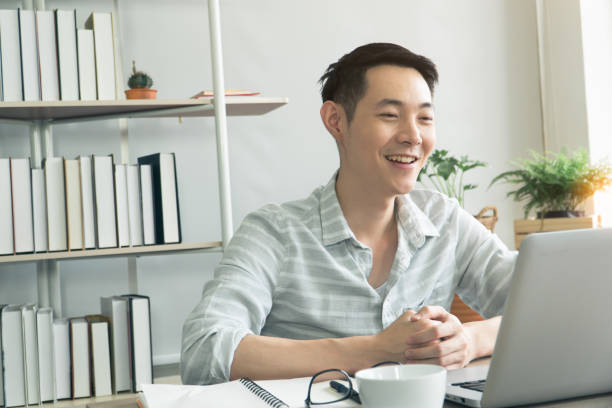 istock Happy smiling Asian young man working on laptop 1329695452