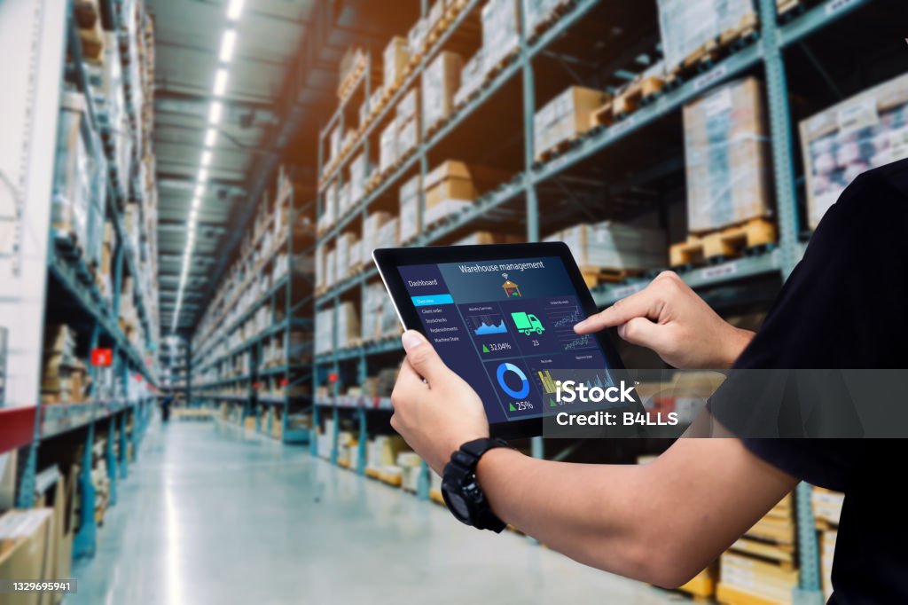 Smart warehouse management system. Worker hands holding tablet on blurred warehouse as background Warehouse Stock Photo