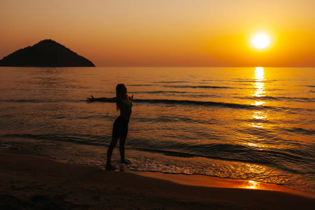 istock Young woman practicing sun salutations on the beach 1329697185