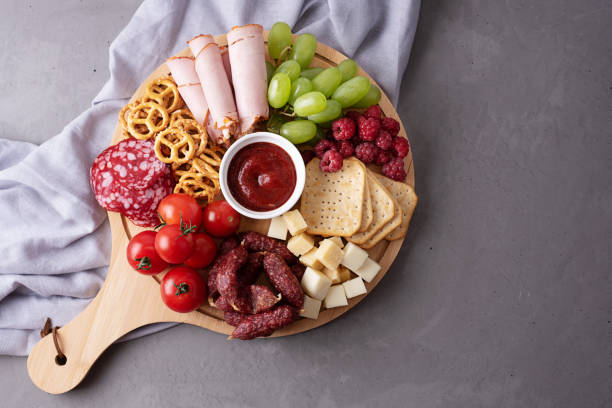 istock Various snacks on a round charcuterie board on a gray background, party a appetizer. 1329698341