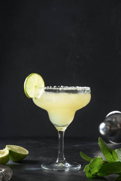 istock Classic Margarita cocktail with lime and ice cube on black background. Freshness summer alcoholic beverage. 1329699583