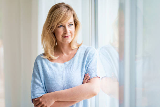 istock Attractive woman daydreaming while standing at the window 1329700454