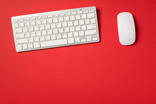 Top view photo of white wireless keyboard and mouse on isolated vivid red background with copyspace