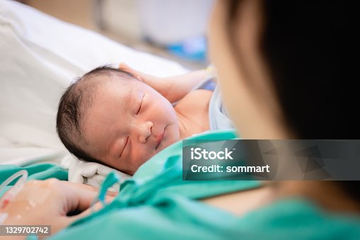 istock Young mother holding her newborn baby who sleep first days of life at hospital, love and Mother’s Day concept. 1329702742