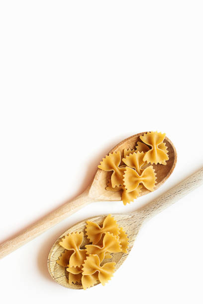 massa de gravata borboleta de trigo integral em colheres de madeira - bow tie pasta italian cuisine bow heap - fotografias e filmes do acervo