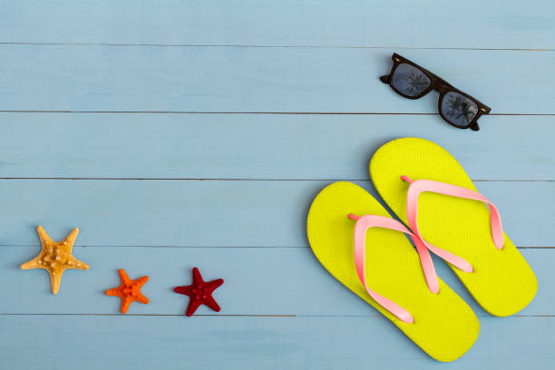 istock Summer time on a cool view on painted light blue wood table with sunglasses, flip flops and starfish 1329703722