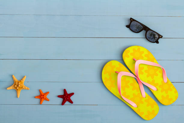istock Summer time on a cool view on painted light blue wood table with sunglasses, flip flops and starfish 1329703923