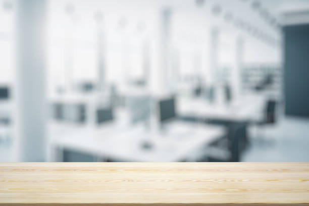 istock Empty wooden table top with light sunny furnished office on background, mock up 1329703972