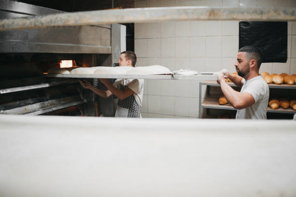 istock Baker taking bread out of oven 1329705138