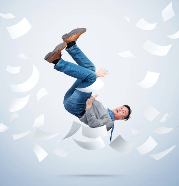 istock Man in office clothes falls down with sheets of paper on light blue background. Falling markets and bankruptcy concept 1329705872