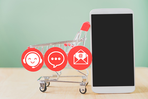 mobile phone and contact symbol on red circle paper  with shopping cart for contact us, question and answer ,new normal lifestyle, social distancing, online shopping and delivery