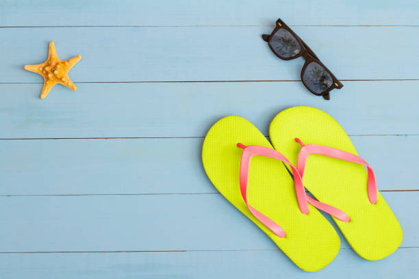 istock Summer time on a cool view on painted light blue wood table with sunglasses, flip flops and starfish 1329705990