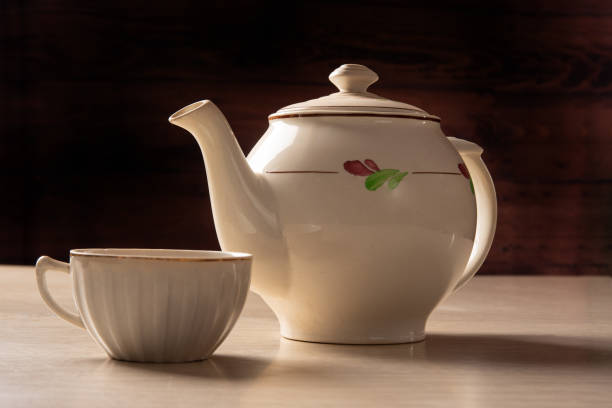 istock Teapot and cup of tea on a formica table, dark background, selective focus. 1329709067